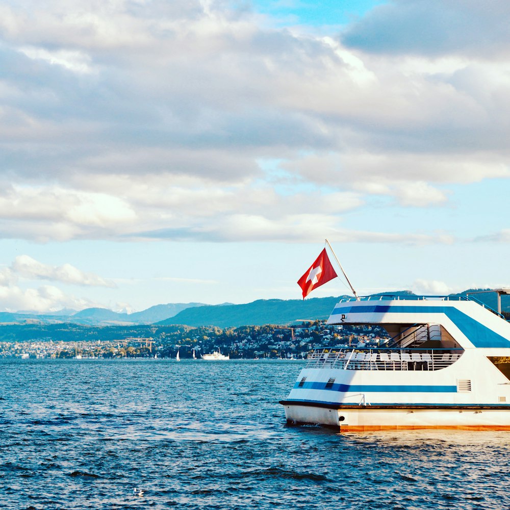 white and blue boat on sea under cloudy sky during daytime