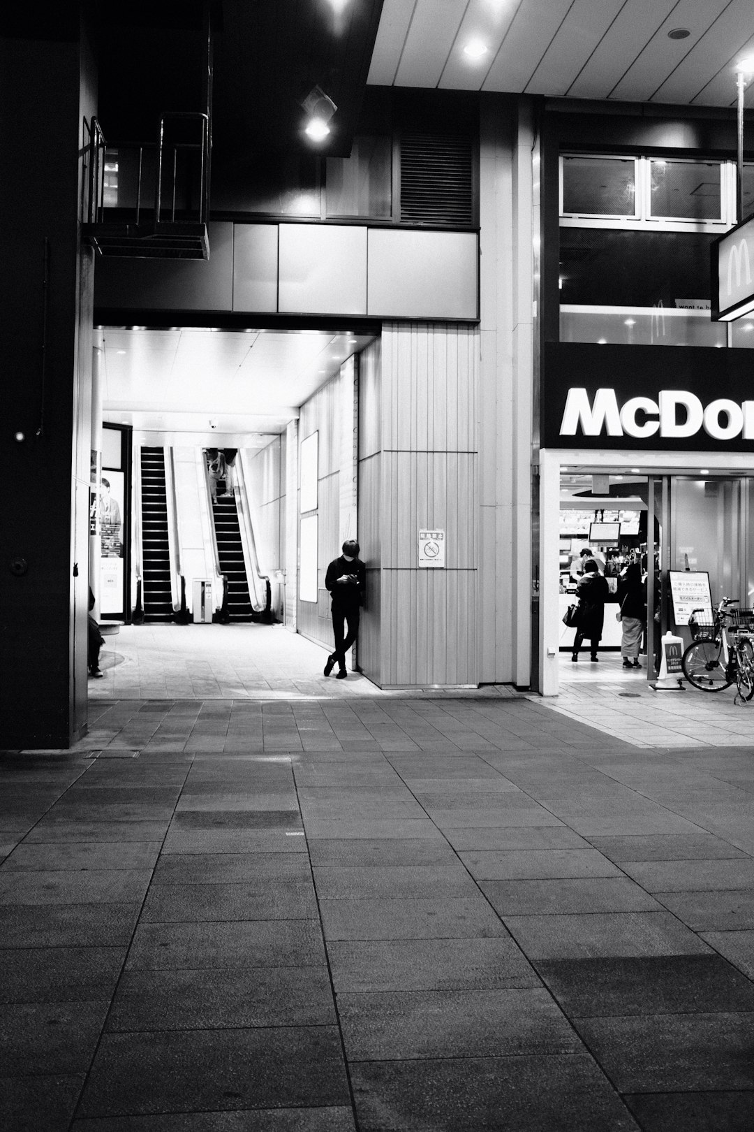 grayscale photo of man walking on sidewalk