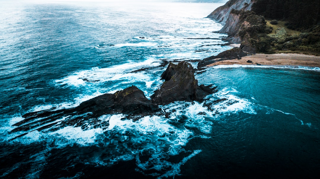 ocean waves crashing on rocky shore during daytime