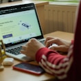 person using macbook pro on brown wooden table