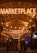 A warmly lit marketplace entrance at night, with illuminated letters overhead spelling 'MARKETPLACE'. Strings of glowing bulbs create a cozy and inviting atmosphere. People walk beneath the canopy, and a bar with a neon sign can be seen on the right.