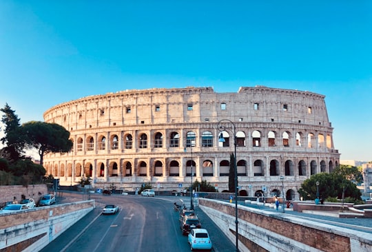 cars parked on road near brown concrete building during daytime in Colosseum Italy