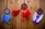 Three dreamcatchers with colorful feathers hang against a wooden wall backdrop. The left dreamcatcher features blue feathers and a central blue bead. The middle one has vibrant red and orange feathers with a decorative icon in the center. The right piece displays purple and white feathers with a central purple embellishment.