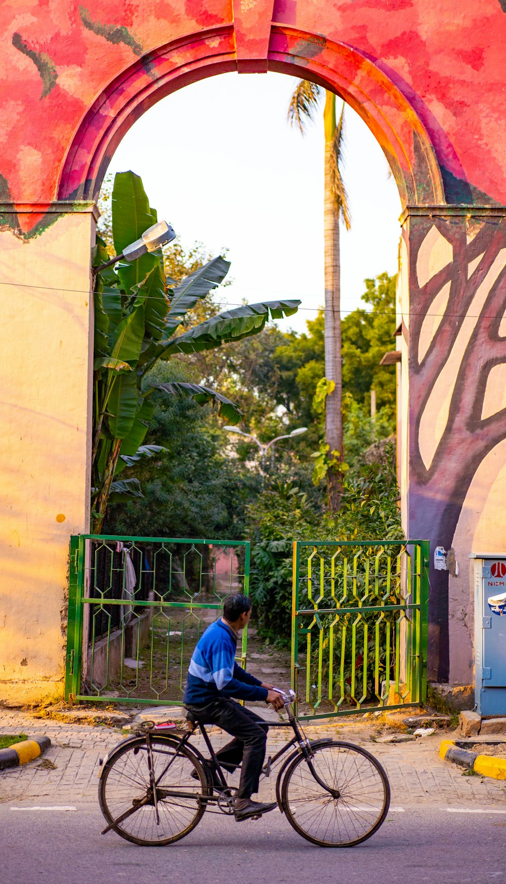 man in blue jacket standing near green metal gate during daytime