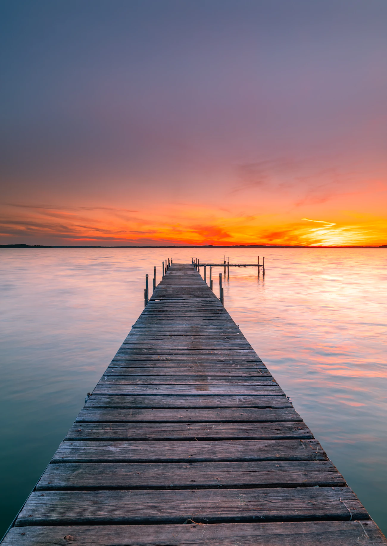 Wooden dock extending over calm water at sunset