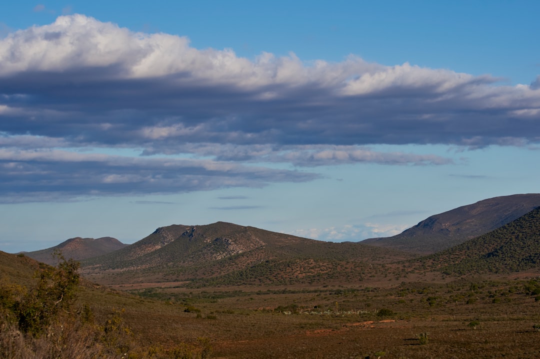 green and brown mountains under white clouds and blue sky during daytime