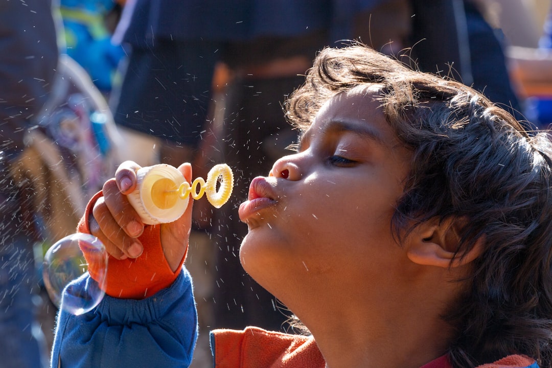 girl in red and blue shirt blowing bubbles