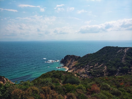 green and brown mountain beside blue sea under blue and white cloudy sky during daytime in Çanakkale Turkey