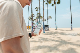 A robot and a person carrying delivery boxes on a sandy beach.