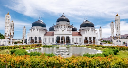 white and blue concrete building near body of water during daytime in Baiturrahman Grand Mosque Indonesia