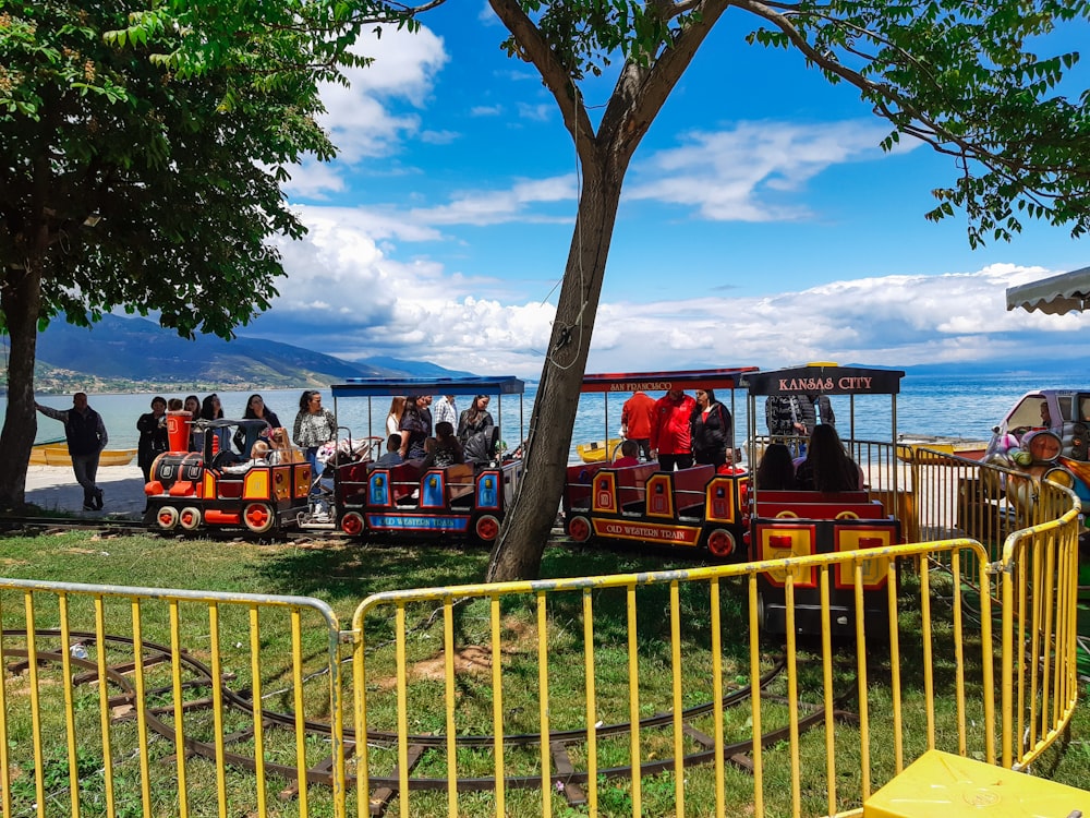 people riding on red and yellow roller coaster during daytime