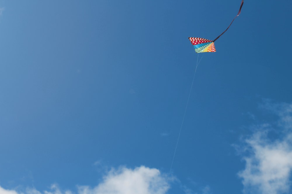 roter gelber und blauer Drachen, der tagsüber unter blauem Himmel fliegt