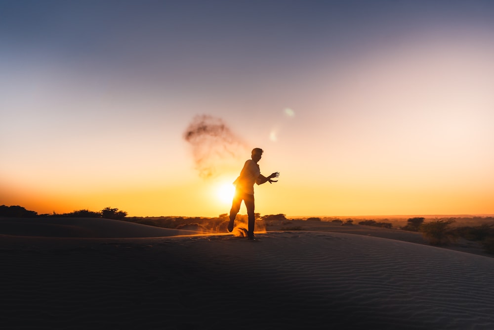 silhouette dell'uomo che corre sulla sabbia durante il tramonto