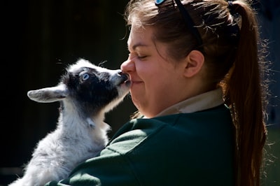 woman in green jacket holding white and black dog federal colonial teams background