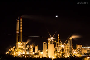 Evening view of a paper mill with lights glowing behind large windows, showcasing ongoing production.