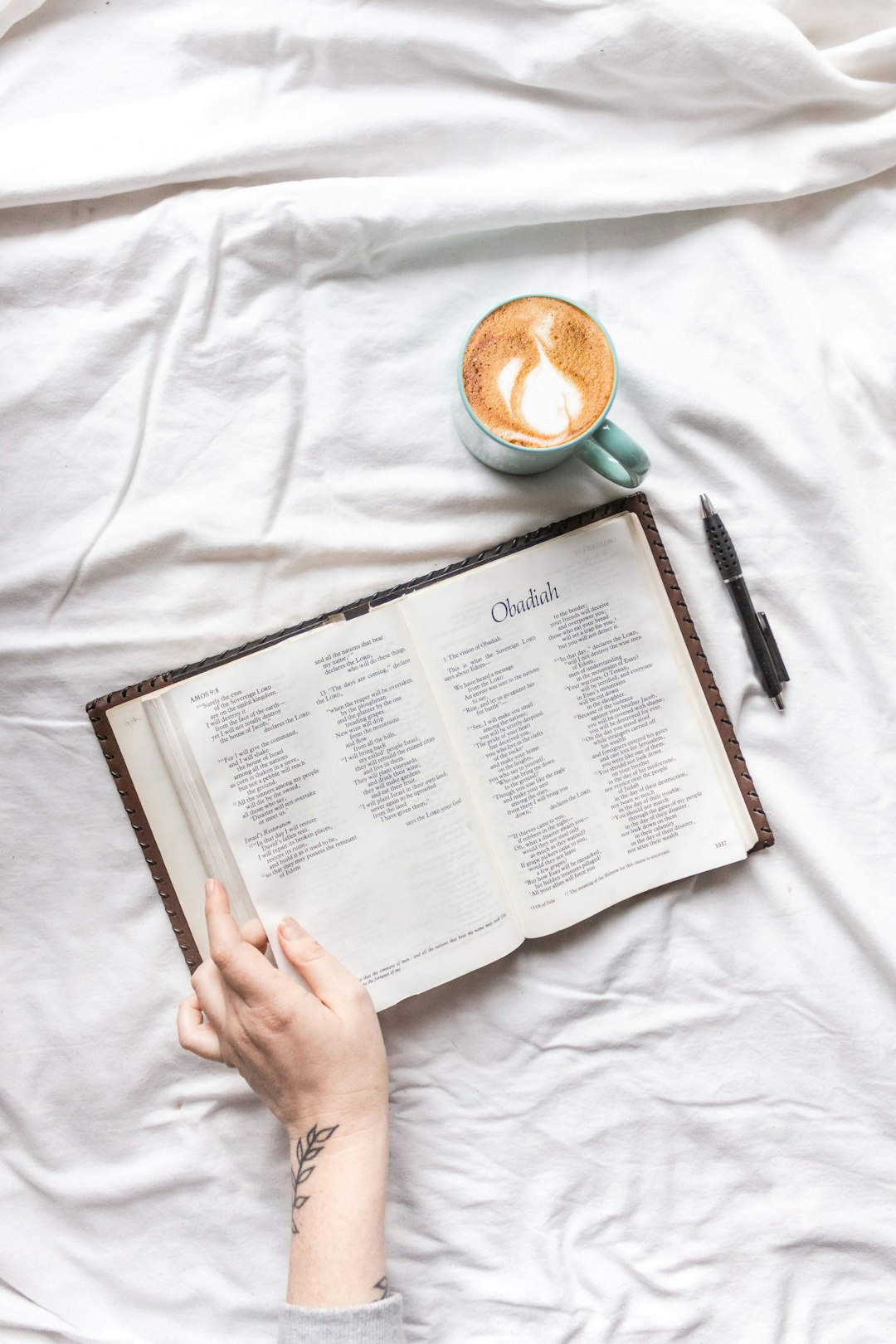 person holding white book page on white textile