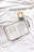 A book is laid open on a white fabric surface next to a cappuccino in a light green cup. Beside the book is a black pen. The book appears to be a Bible open to the Book of Jonah.