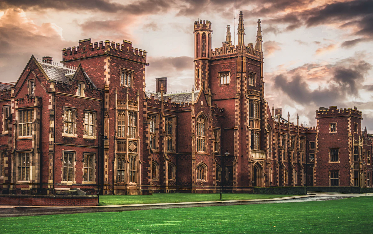 A university building exterior with tall windows, seen against a cloudy sky