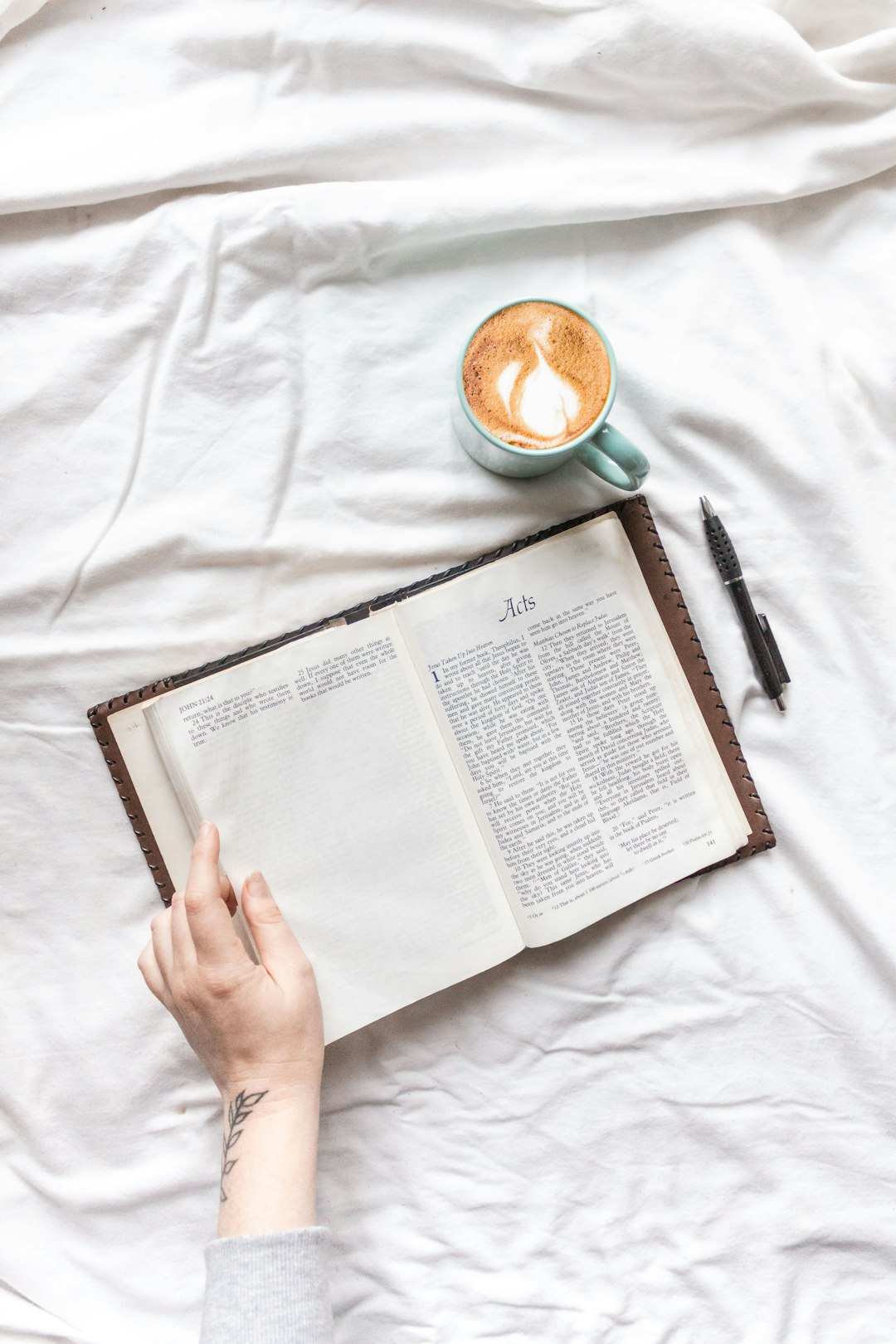 person reading book on white textile