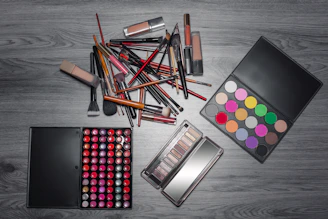 Close-up shot of elegant makeup brushes and vibrant lipsticks arranged on a sleek black surface.