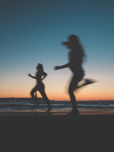Dynamic shot of a man and woman jogging at sunrise, showcasing energy and performance.