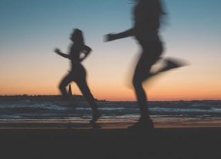 silhouette of woman jumping on beach during sunset