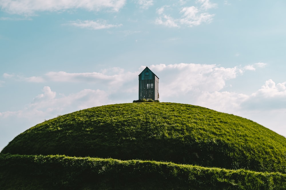 white and black house on green hill under white clouds and blue sky during daytime