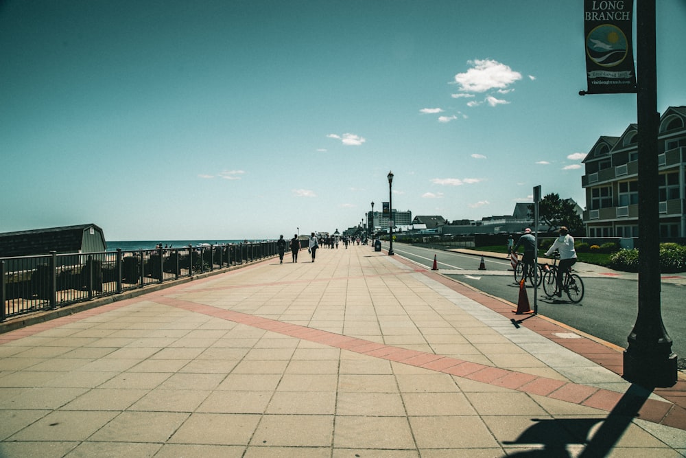 people walking on sidewalk near sea during daytime