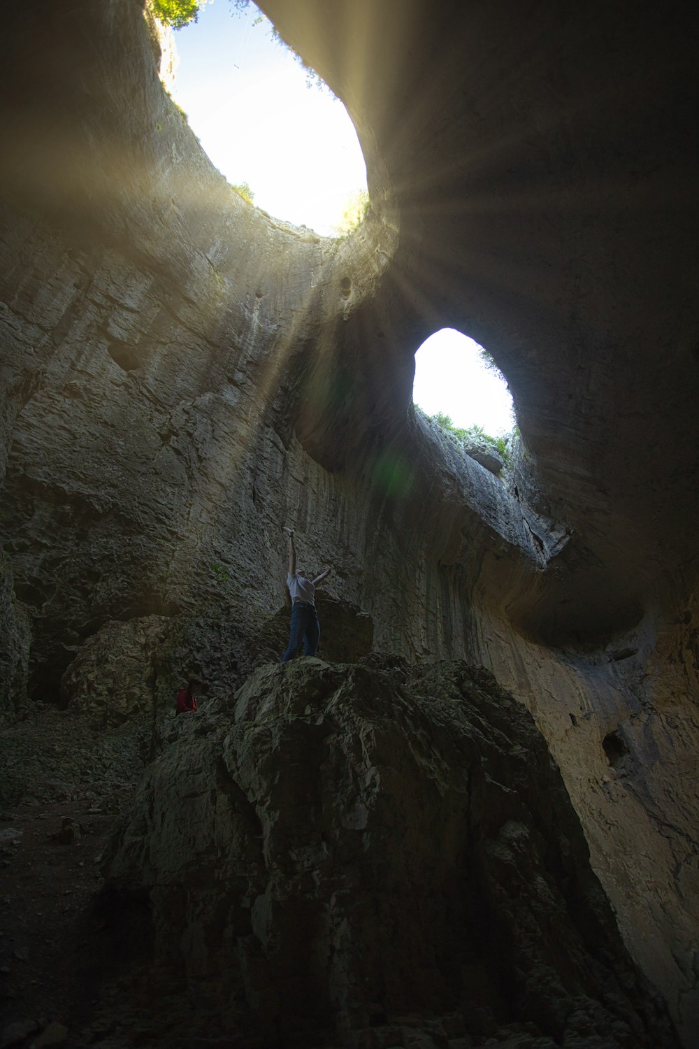 person in blue jacket standing on cave during daytime
