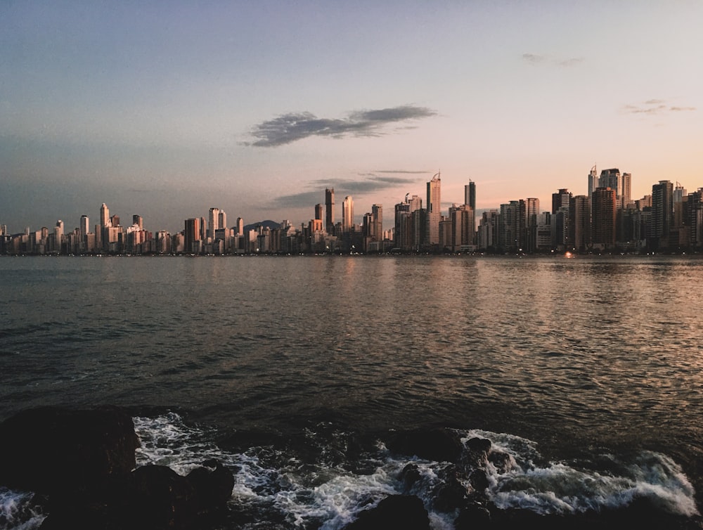 city skyline across body of water during sunset