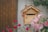 A handcrafted wooden mailbox with intricate details, mounted on a sturdy post in front of a cozy house.