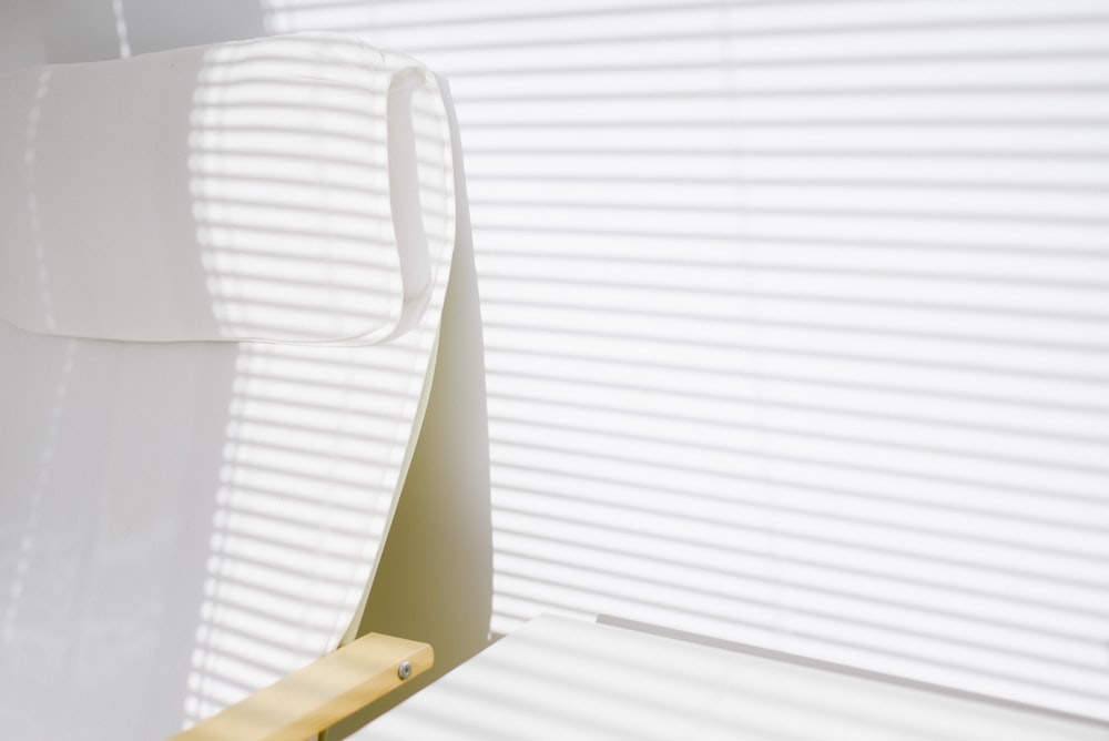 white plastic chair beside white window blinds