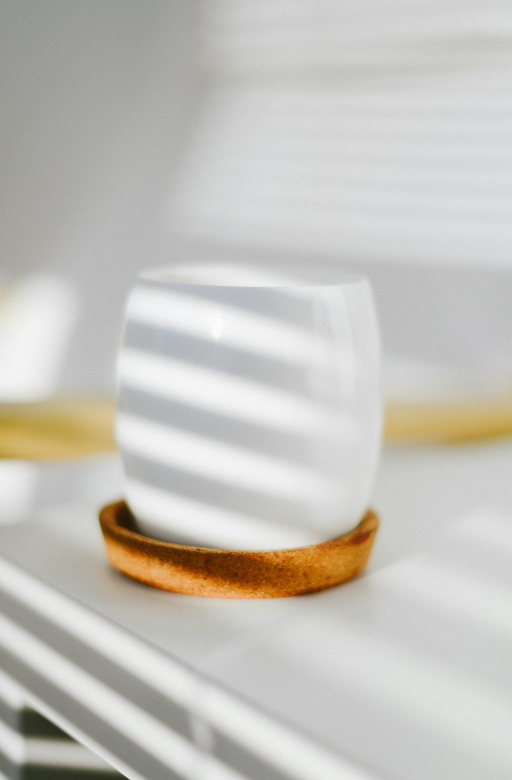 white and brown striped ceramic mug on white table