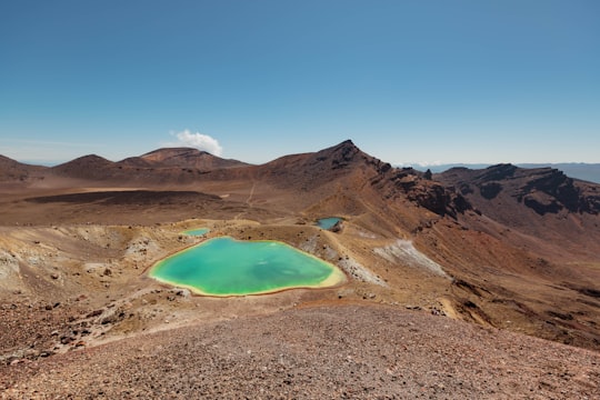 brown mountain near blue lake under blue sky during daytime in Mount Tongariro New Zealand