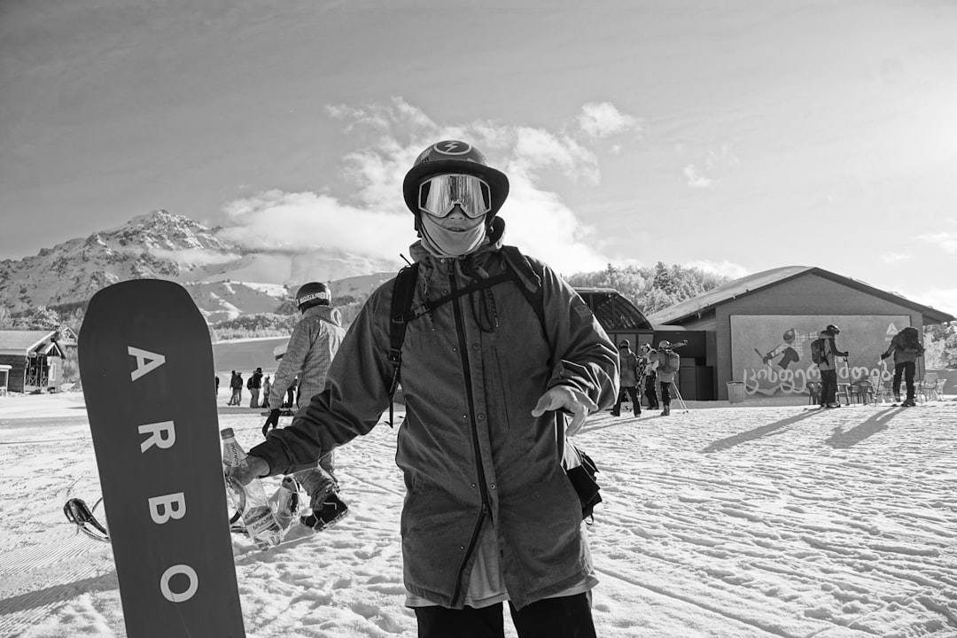 man in black jacket and pants holding snowboard