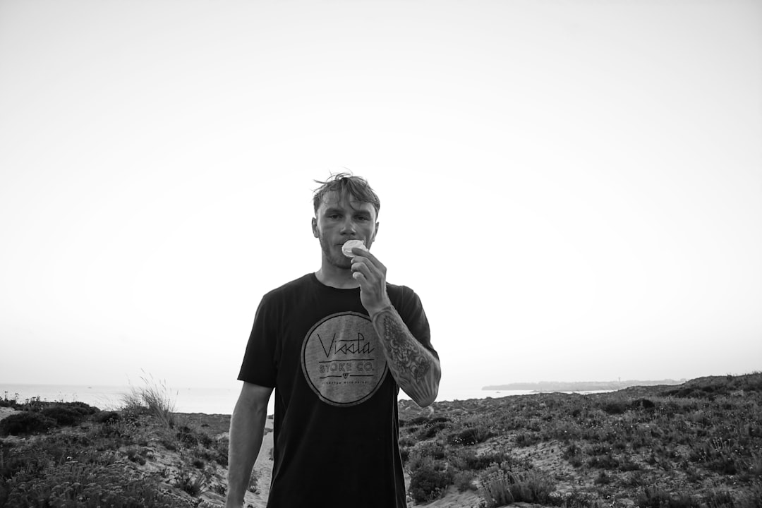 man in black crew neck t-shirt standing on brown grass field during daytime