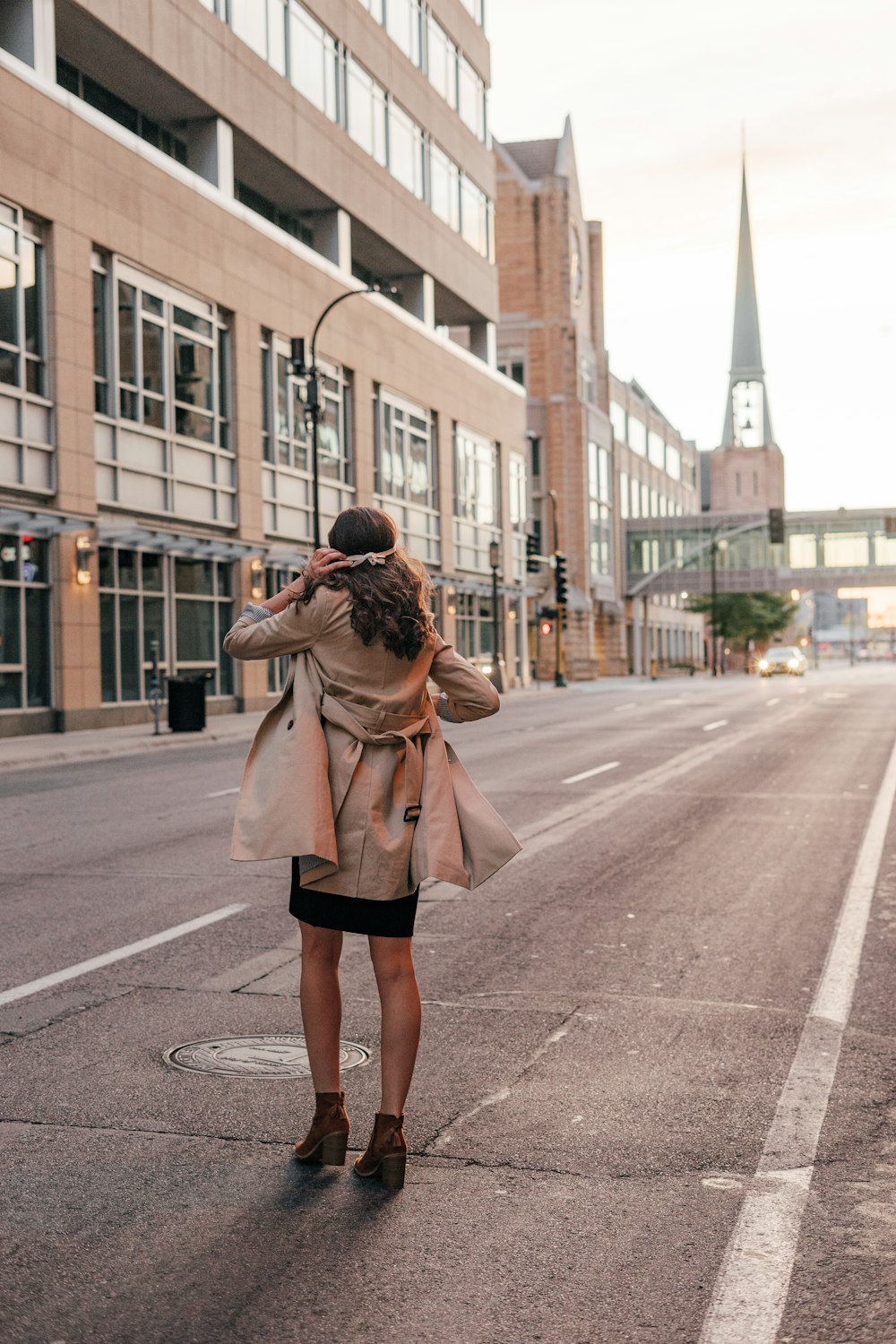 woman in brown coat standing on road during daytime