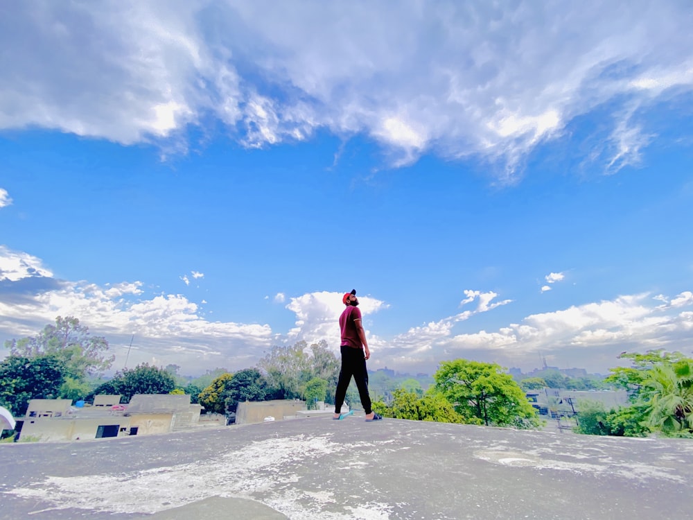 woman in red long sleeve shirt and black pants standing on gray concrete pavement during daytime