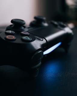 Close-up of a sleek PS5 console with its controller resting on a dark blue surface