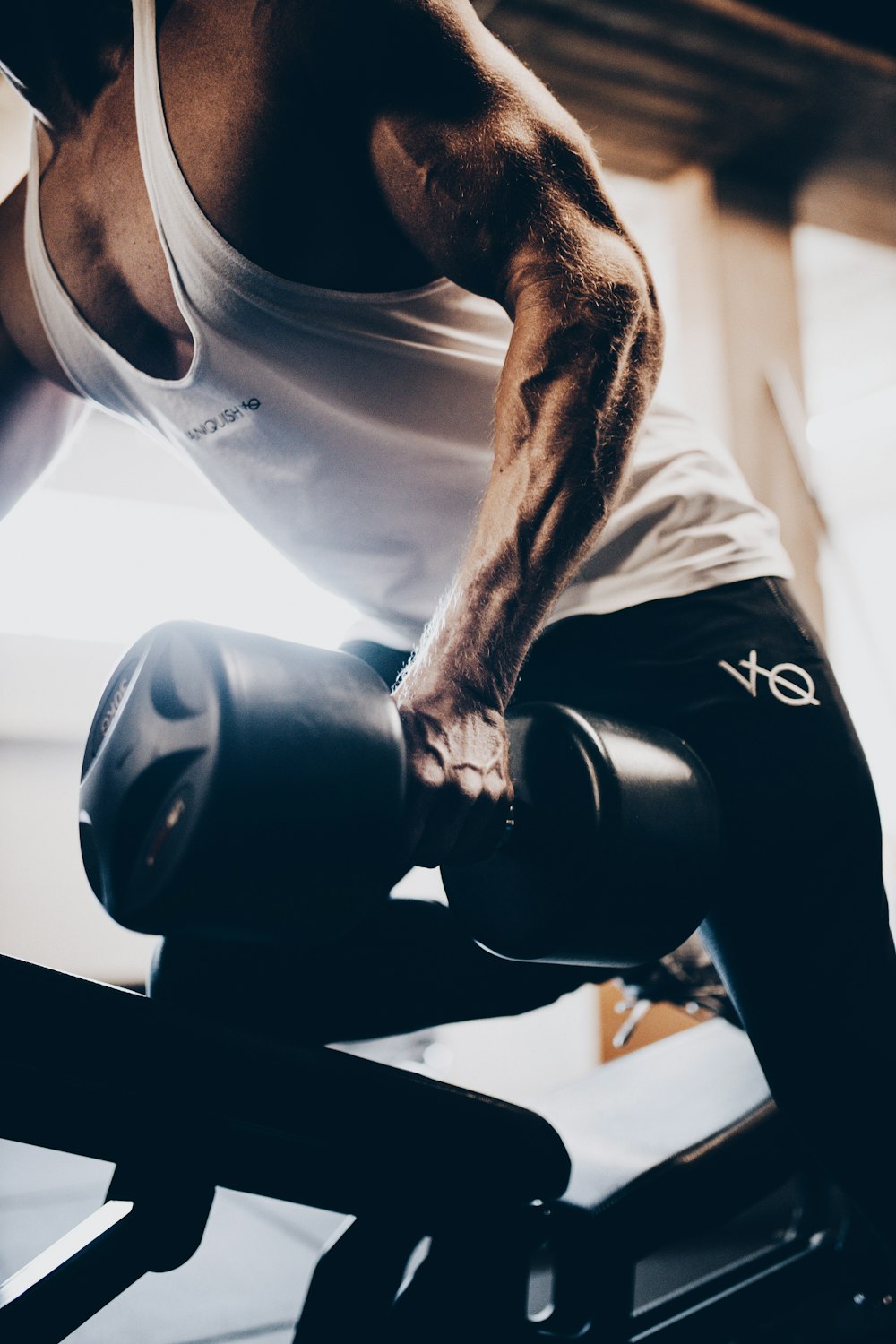 man in blue tank top and black shorts holding black dumbbell