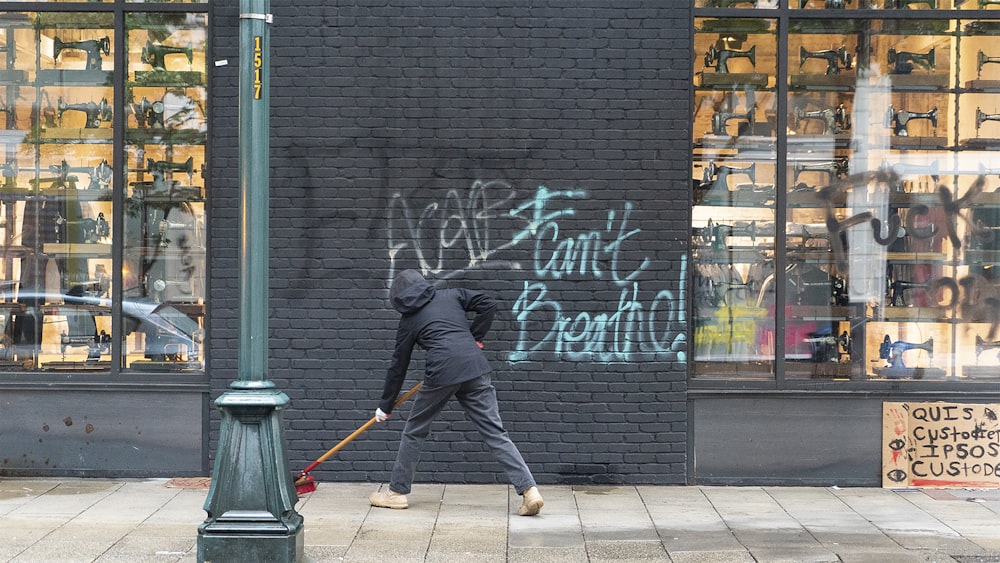 man in black jacket and black pants walking on sidewalk during daytime