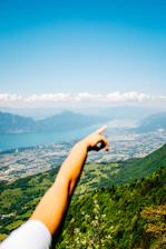 A smiling local guide pointing towards a scenic valley under a clear blue sky.