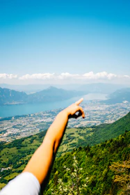 A smiling local guide pointing towards a scenic valley under a clear blue sky.