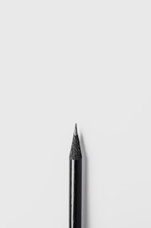 Close-up of a sleek, modern pencil with no visible point, resting on a wooden desk.