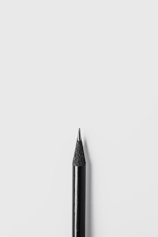 Close-up of a sleek, modern pencil with no visible point, resting on a wooden desk.