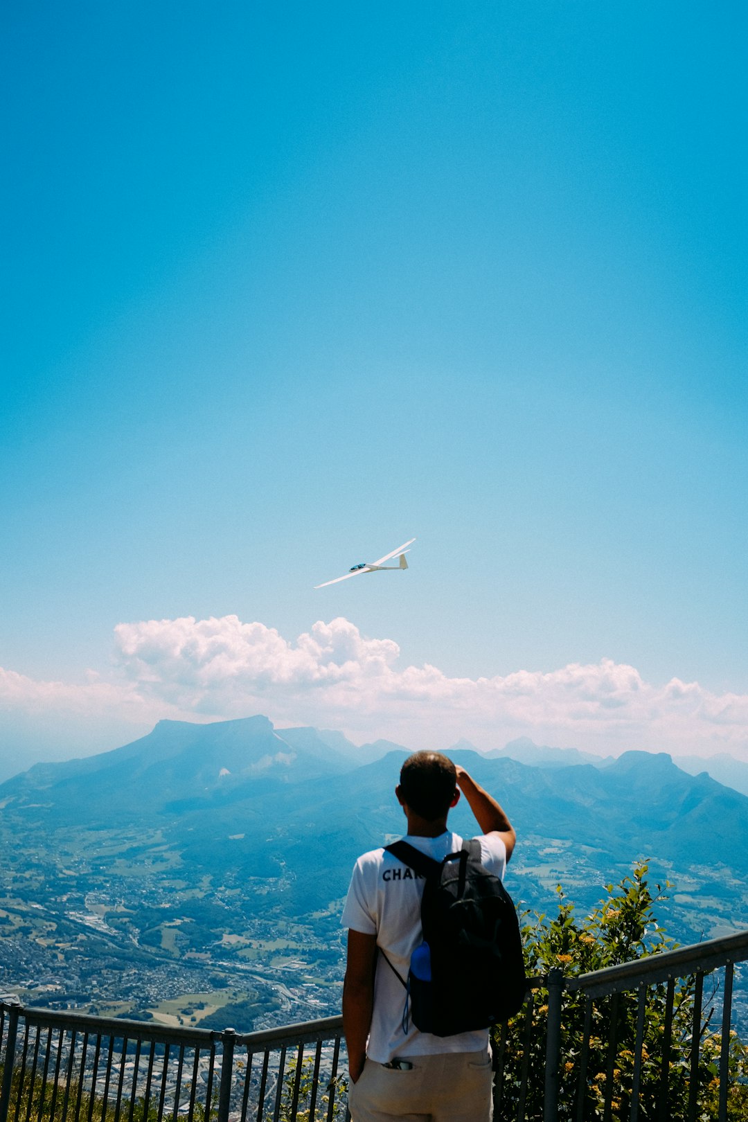 man in white shirt sitting on rock looking at white airplane