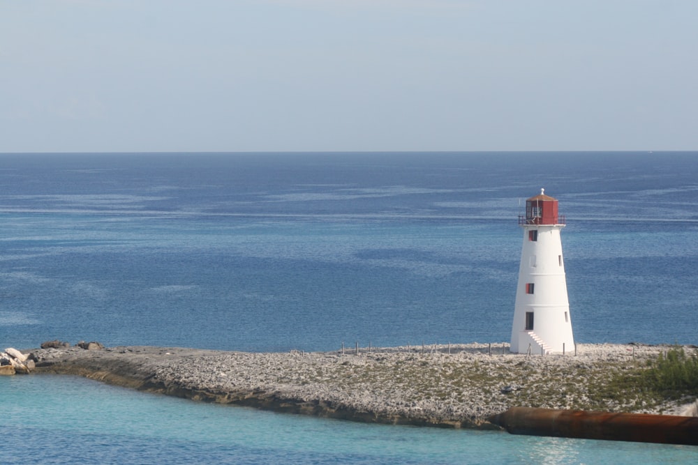 white and red lighthouse near blue sea during daytime