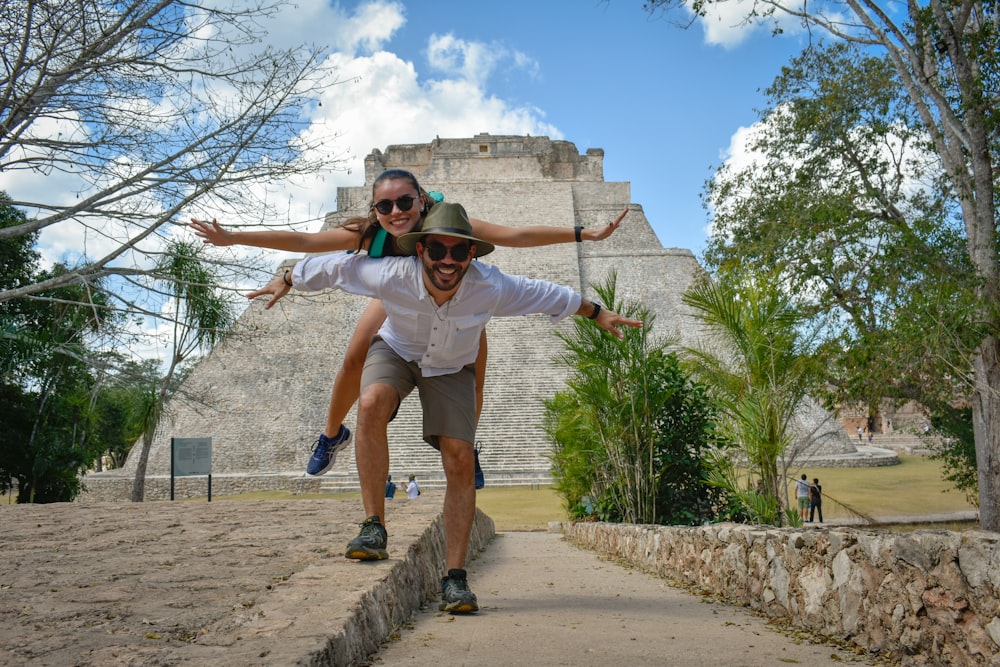 man in white t-shirt and brown shorts jumping on brown concrete pathway during daytime