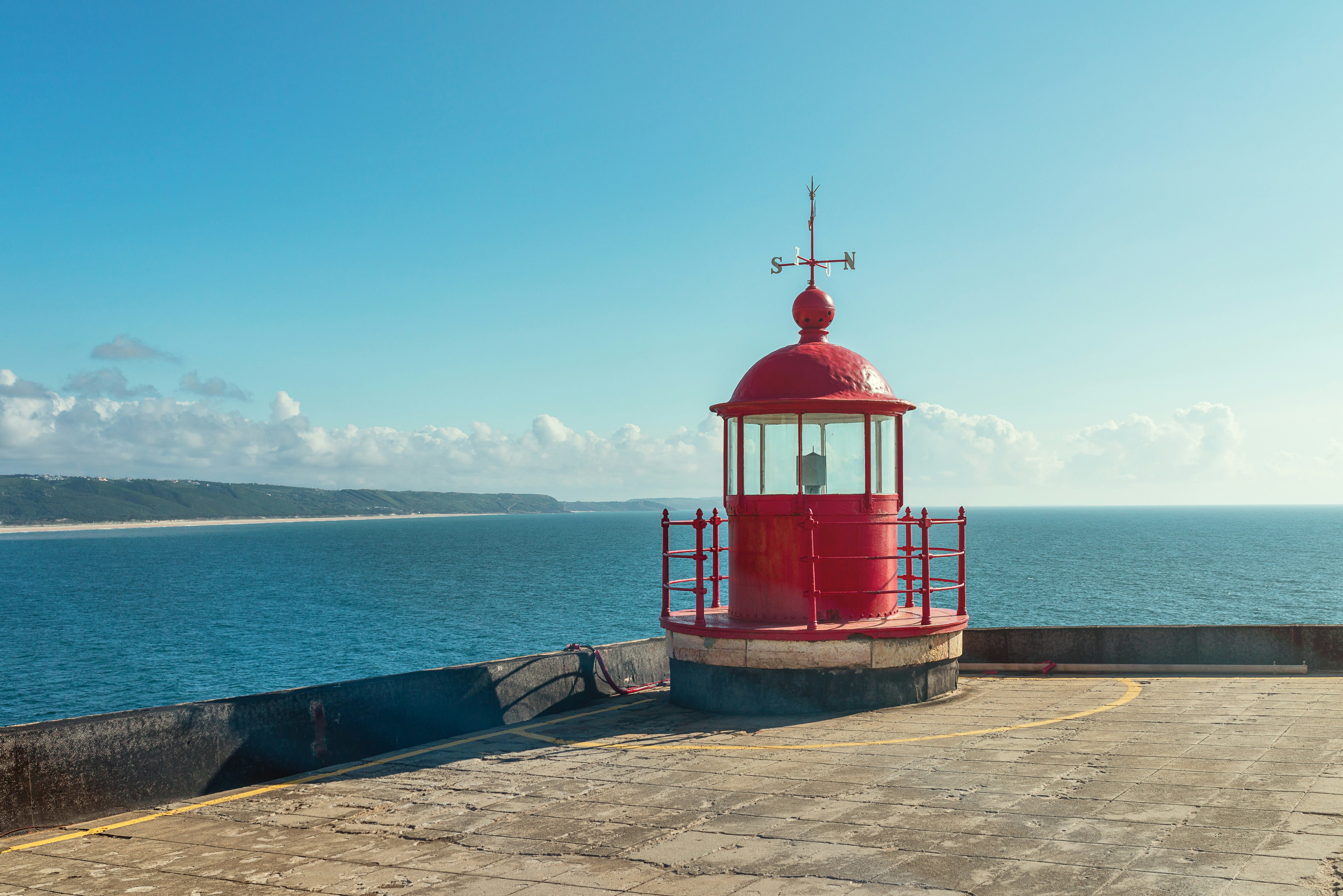 red and white wooden house near sea under blue sky during daytime