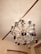 A ceiling chandelier adorned with crystal-like decorations and various hanging mugs and small ornaments. The chandelier's ornate design features metallic and glass elements that reflect the light from multiple bulbs placed at the top.